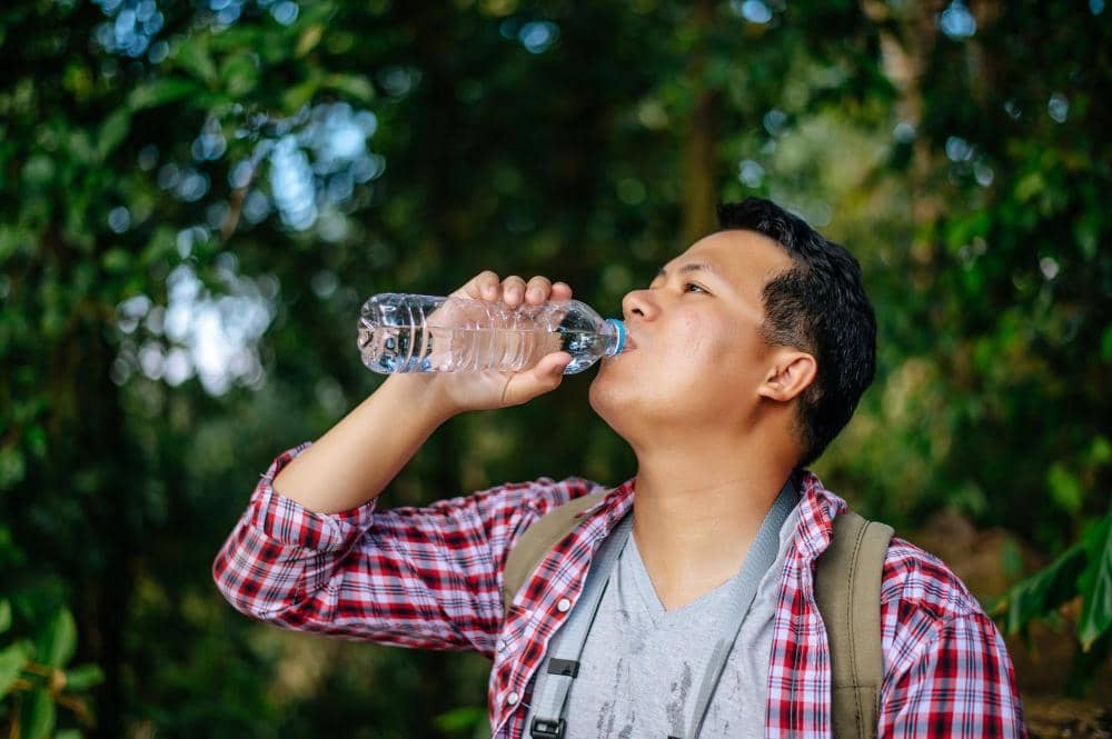 ilustrasi pria minum air mineral saat cuaca panas