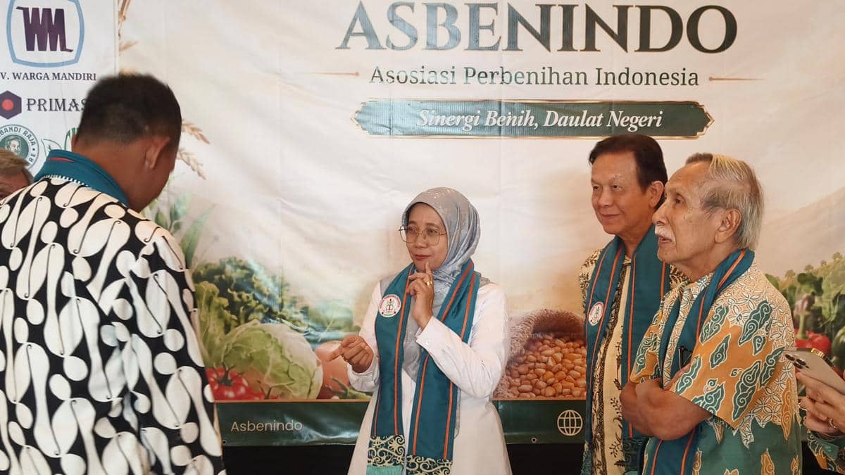 Beberapa orang mengenakan selendang biru berbincang di acara Asosiasi Perbenihan Indonesia dengan latar spanduk bertuliskan Asbenindo.