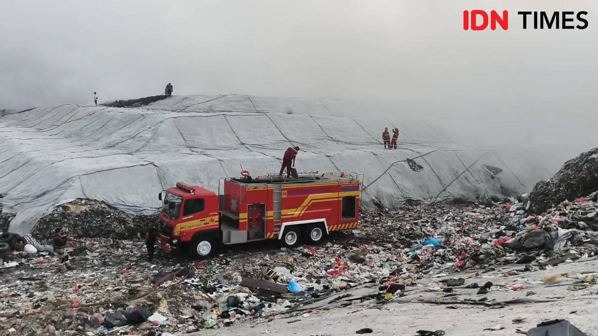 Mobil pemadam kebakaran dan petugas berupaya memadamkan api di area TPA Jatiwaringin yang tertutup asap tebal dan tumpukan sampah.