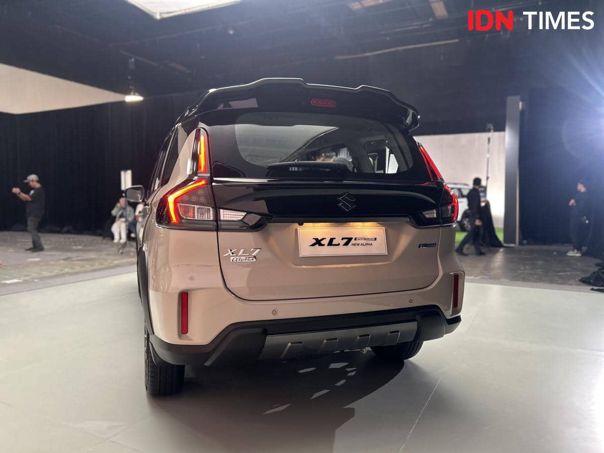 Tampak belakang mobil Suzuki New XL7 Alpha berwarna krem dengan lampu belakang menyala di area studio pemotretan.