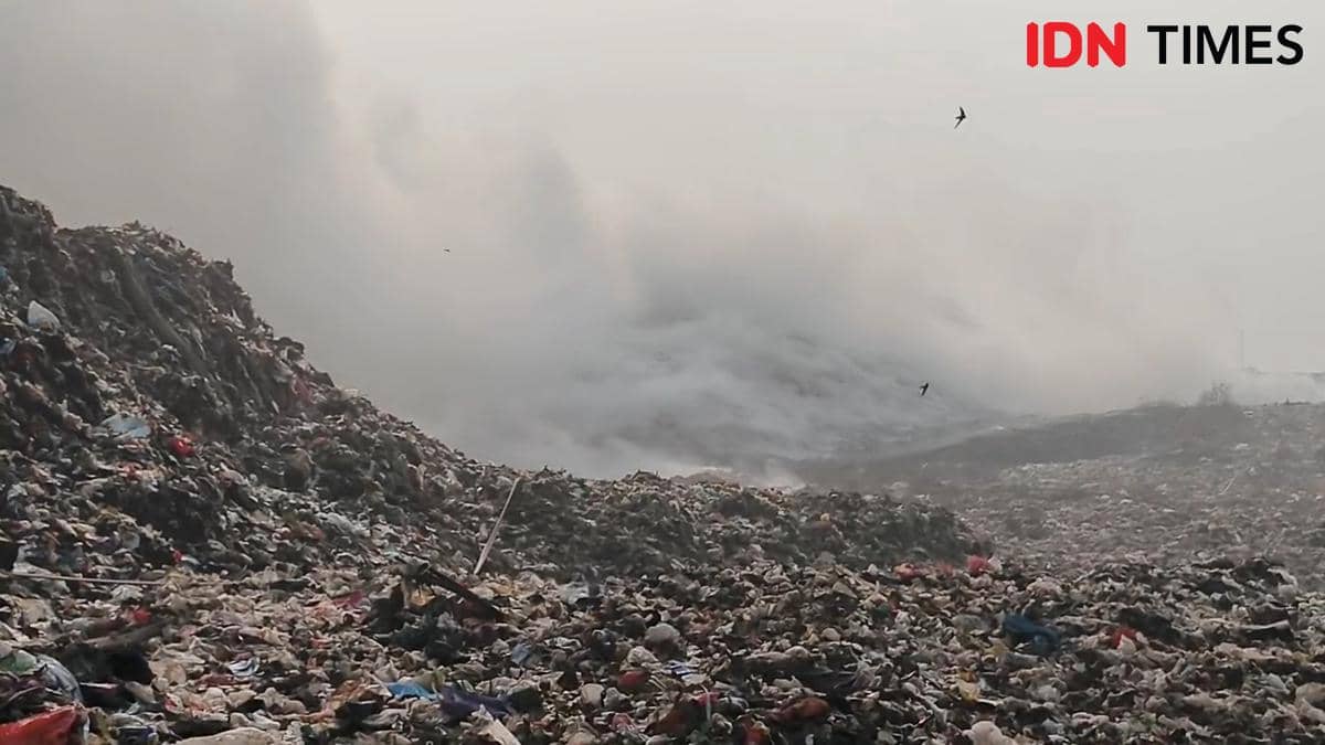 Asap tebal mengepul dari tumpukan sampah besar di TPA Jatiwaringin akibat kebakaran yang melanda area pembuangan akhir.