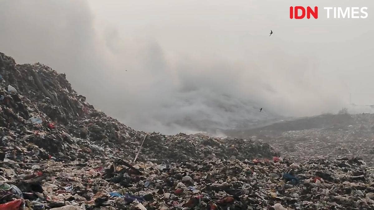 Asap tebal mengepul dari tumpukan sampah besar di TPA Jatiwaringin akibat kebakaran yang melanda area pembuangan akhir.