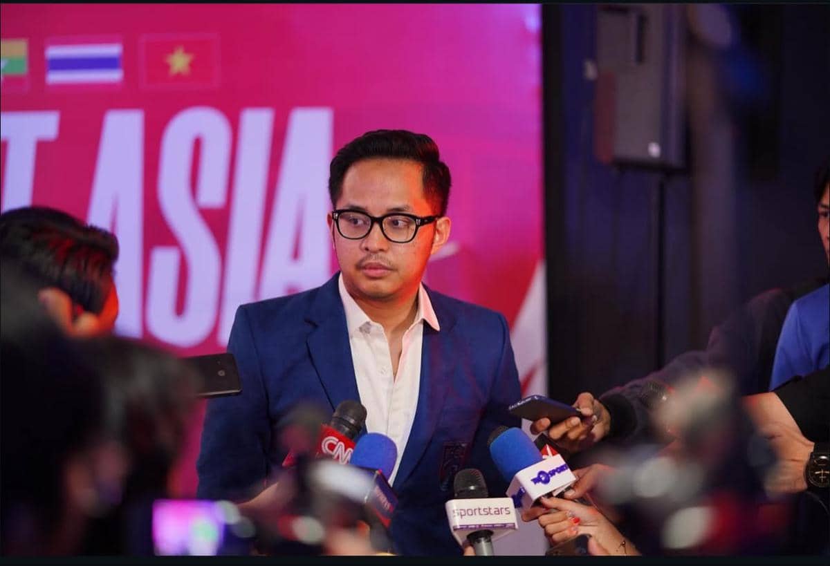 Seorang pria mengenakan jas biru dan kemeja putih sedang diwawancarai oleh sejumlah wartawan dengan mikrofon di depannya.