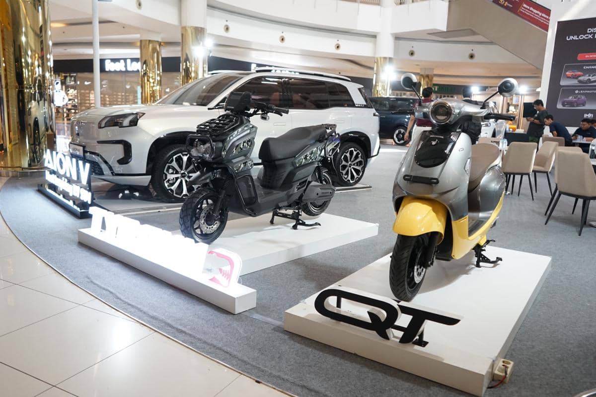 Dua motor listrik Indomobil eMotor dipamerkan di dalam mal bersama sebuah mobil SUV putih di area pameran otomotif.