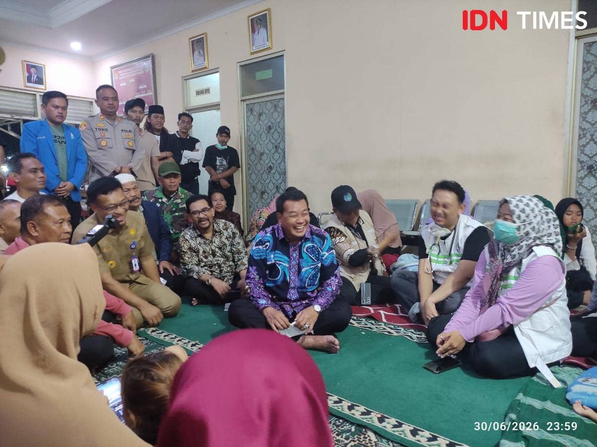 Seorang pejabat daerah duduk bersama warga dan petugas di lokasi pengungsian korban terdampak asap kebakaran TPA Jatiwaringin.