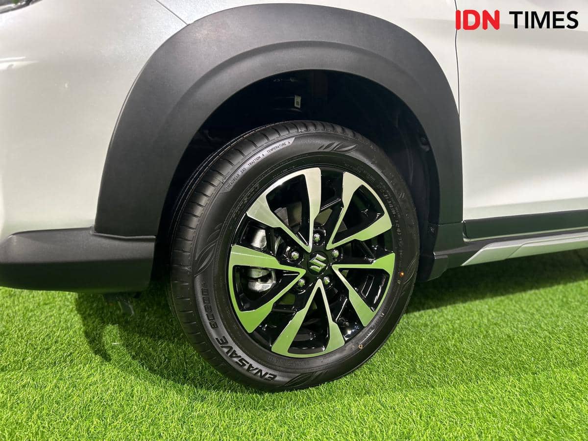 Pelek mobil desain baru dengan kombinasi warna hitam dan perak pada bodi mobil berwarna putih di atas rumput hijau.
