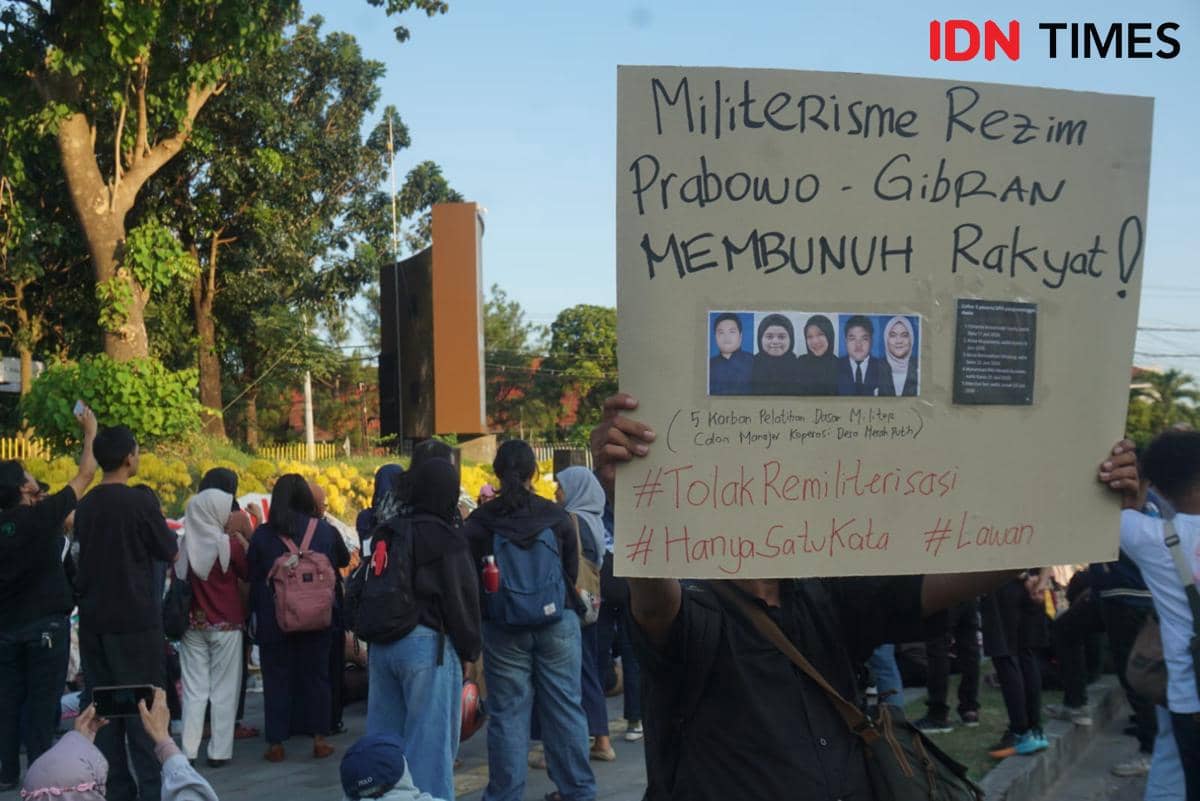 Seorang peserta aksi memegang poster bertuliskan pesan protes dalam demonstrasi 'Suara Ibu Indonesia' di sekitar Bundaran UGM, Sleman.