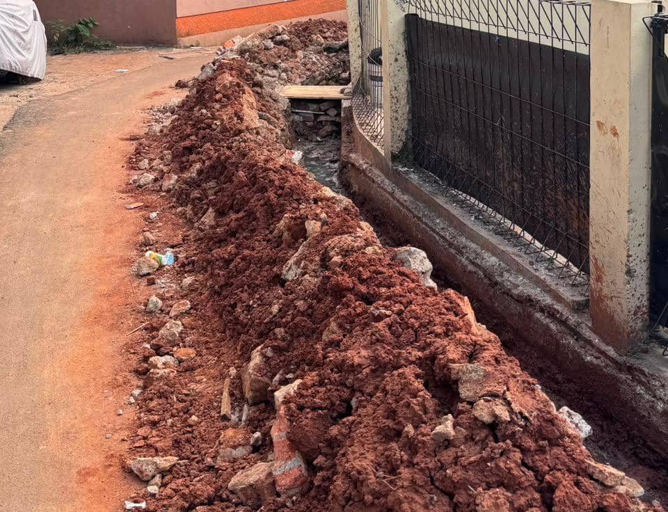 Tumpukan tanah merah hasil galian proyek saluran yang belum selesai di tepi jalan kawasan Pondok Aren, dekat pagar rumah warga.