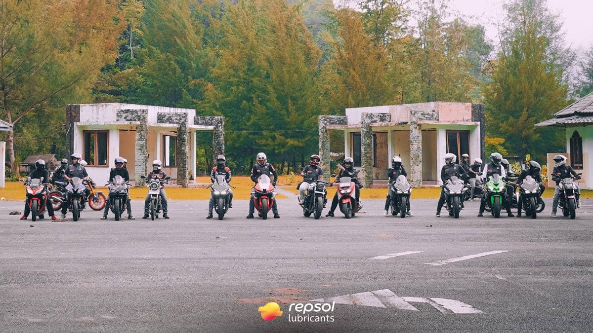 Sejumlah pengendara motor berbaris rapi di area terbuka dengan latar bangunan tua dan pepohonan, dalam kegiatan touring komunitas Repsol di Aceh.