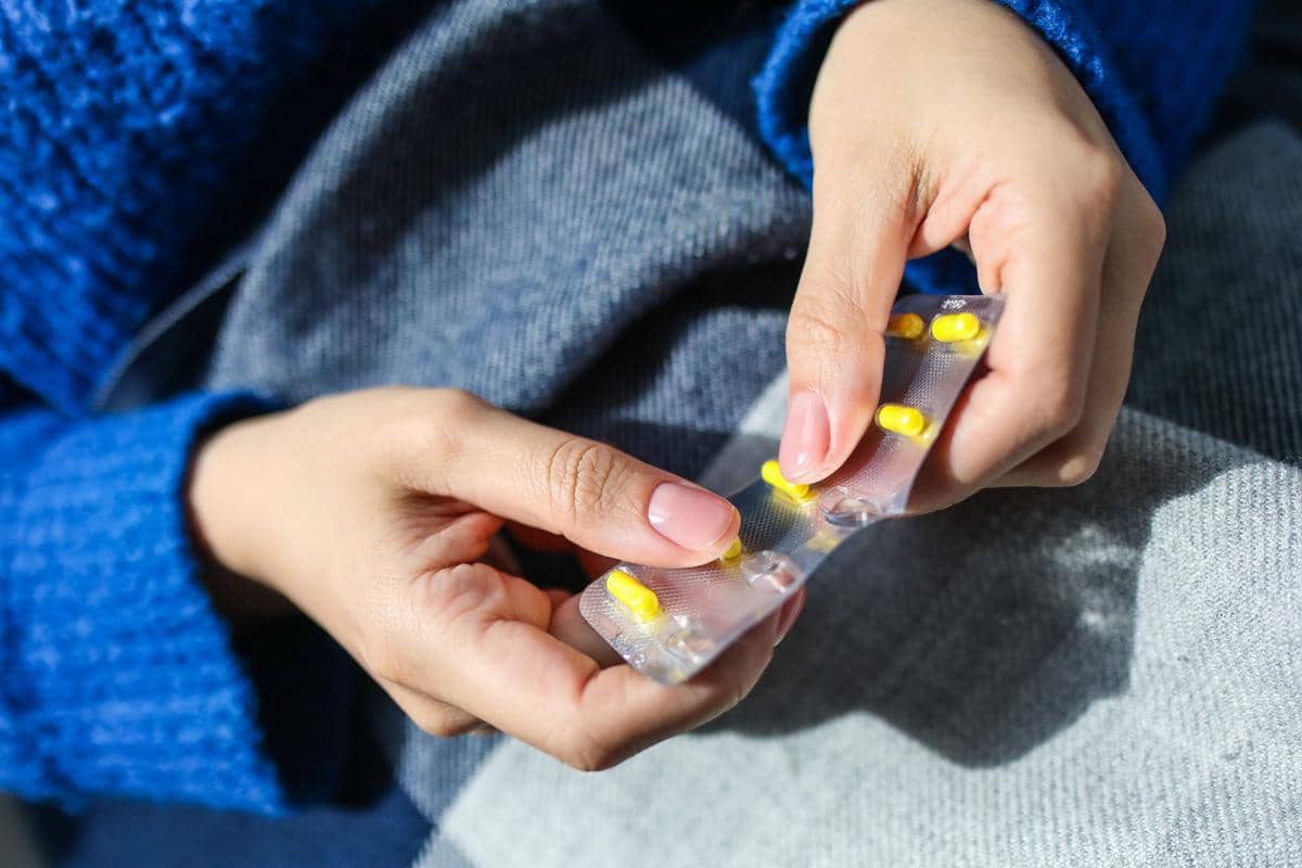 Seseorang memegang blister berisi kapsul kuning ibuprofen, obat antinyeri yang umum digunakan untuk meredakan nyeri dan peradangan.