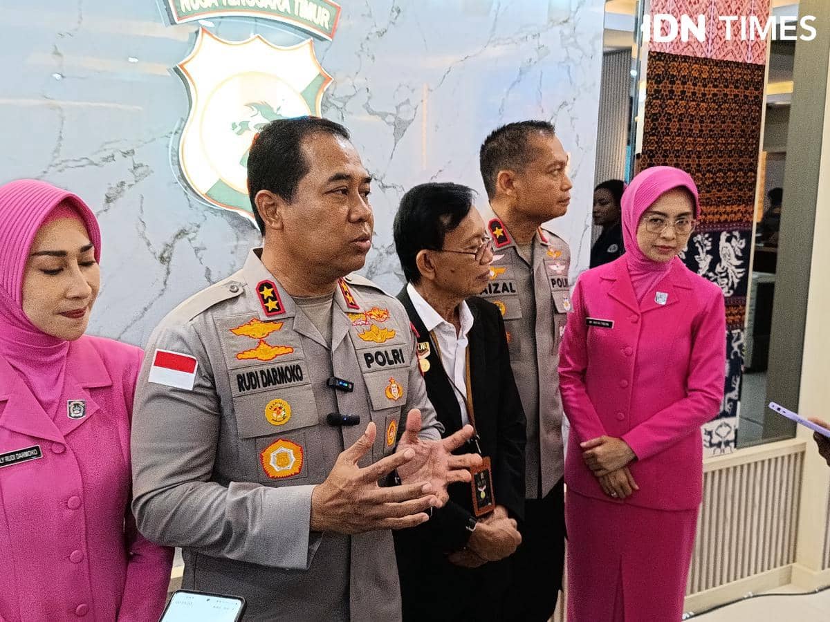 Beberapa pejabat kepolisian dan anggota Bhayangkari berdiri bersama di depan logo Polda Nusa Tenggara Timur saat memberikan keterangan pers.