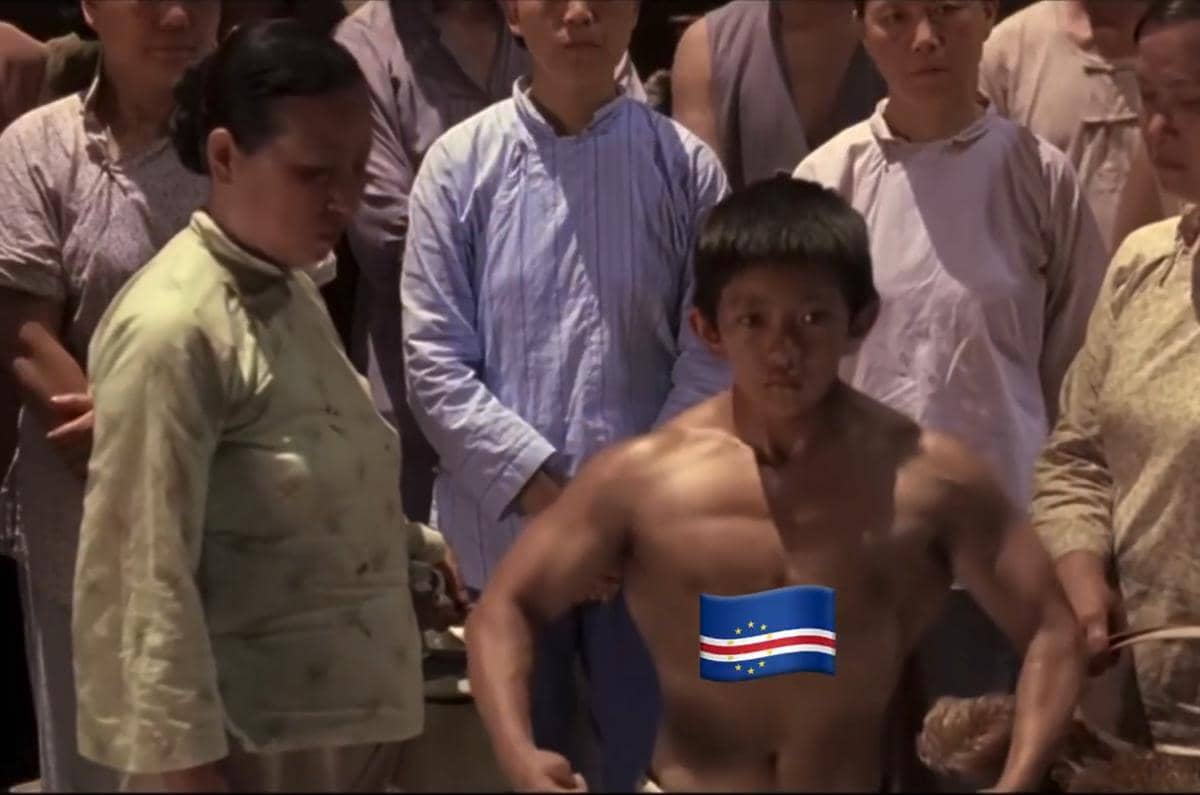 Seorang pria muda berotot tanpa baju berdiri di depan sekelompok orang dengan bendera Cape Verde ditempelkan di tubuhnya.