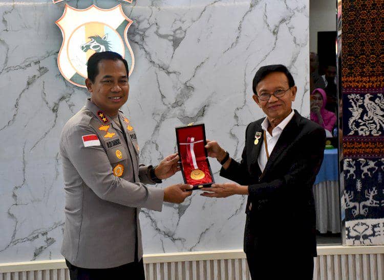 Seorang pejabat kepolisian menerima penghargaan MURI dari seorang pria dalam acara di Polda NTT dengan latar logo kepolisian.