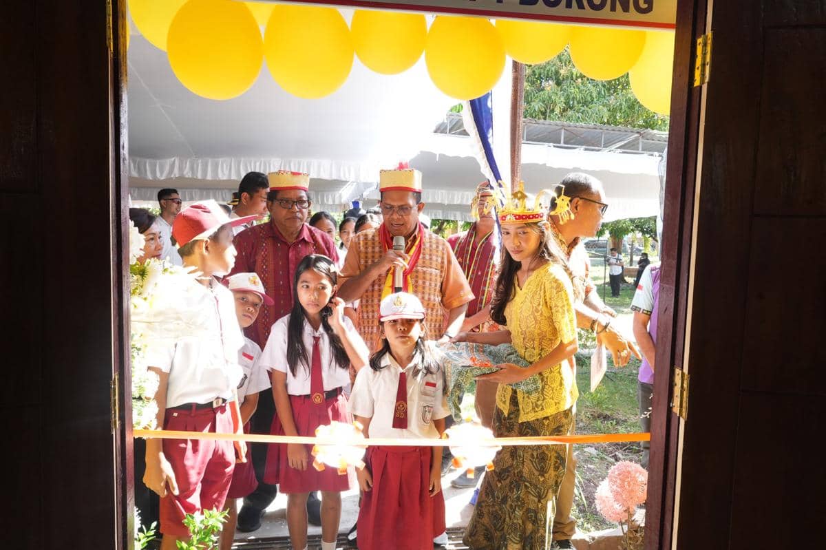 Seorang pejabat berbicara dengan mikrofon saat acara peresmian di SMK Negeri 1 Borong bersama siswa berseragam dan tamu undangan.