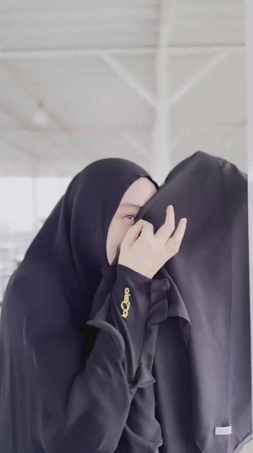 Seorang perempuan mengenakan hijab hitam tampak memeluk seseorang yang juga berhijab di sebuah area beratap terang.