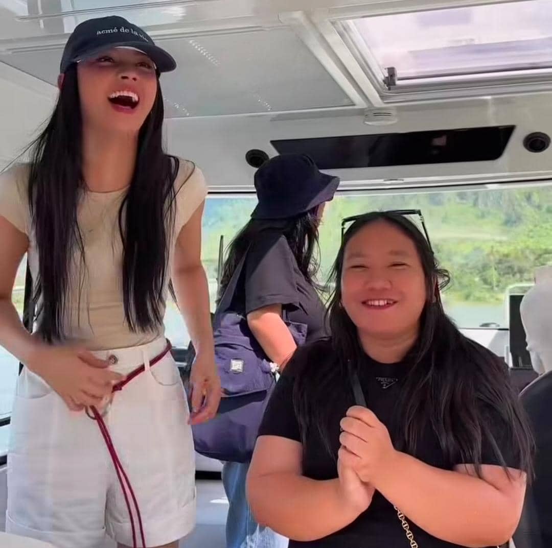 Dua perempuan tersenyum ceria di dalam kapal saat berlibur di Pulau Samosir dengan latar pemandangan hijau di luar jendela.