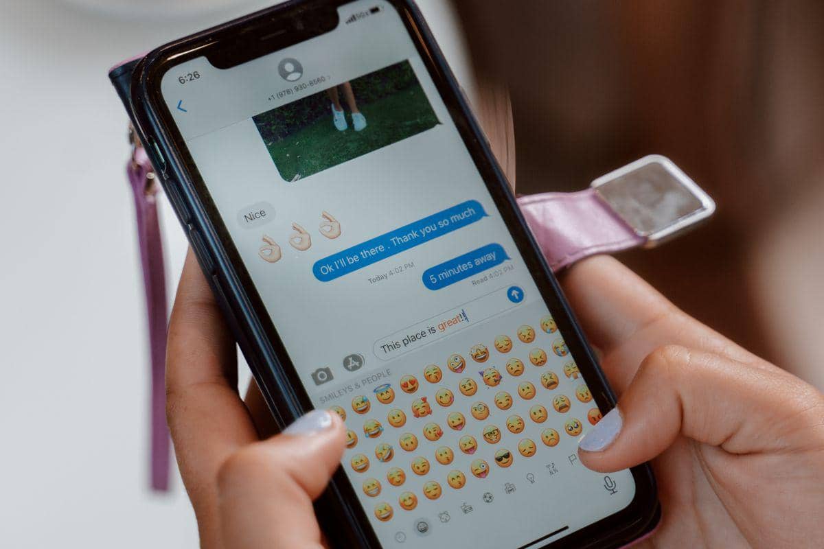 Ilustrasi seseorang menggunakan emoji saat berkomunikasi melalui ponsel.
