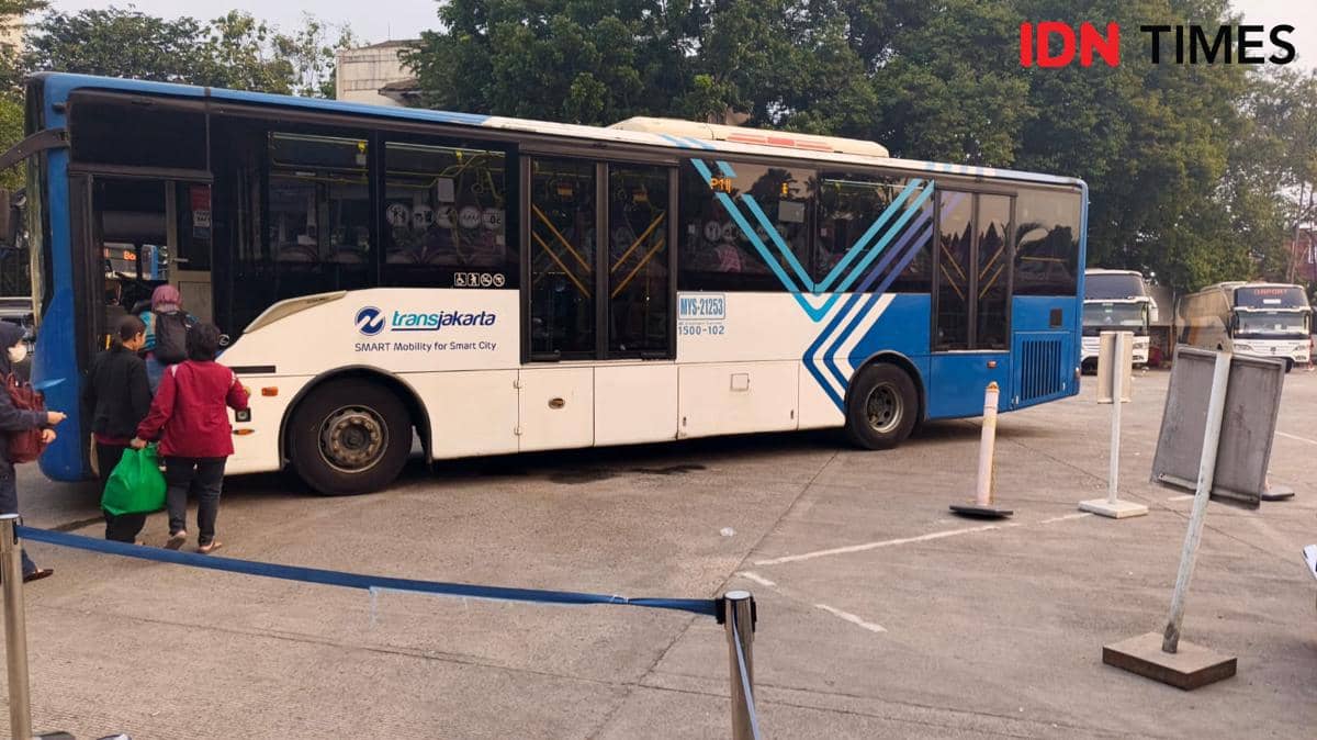 Bus Transjabodetabek P11 rute Bogor-Blok M berhenti di terminal, beberapa penumpang naik ke dalam bus pada pagi hari.