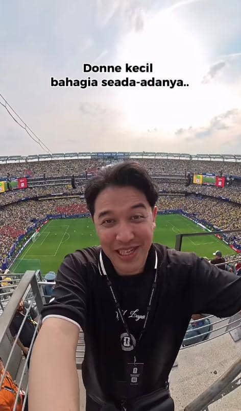 Seorang pria tersenyum sambil berfoto selfie di stadion penuh penonton saat pertandingan Norwegia melawan Brasil di Piala Dunia 2026.