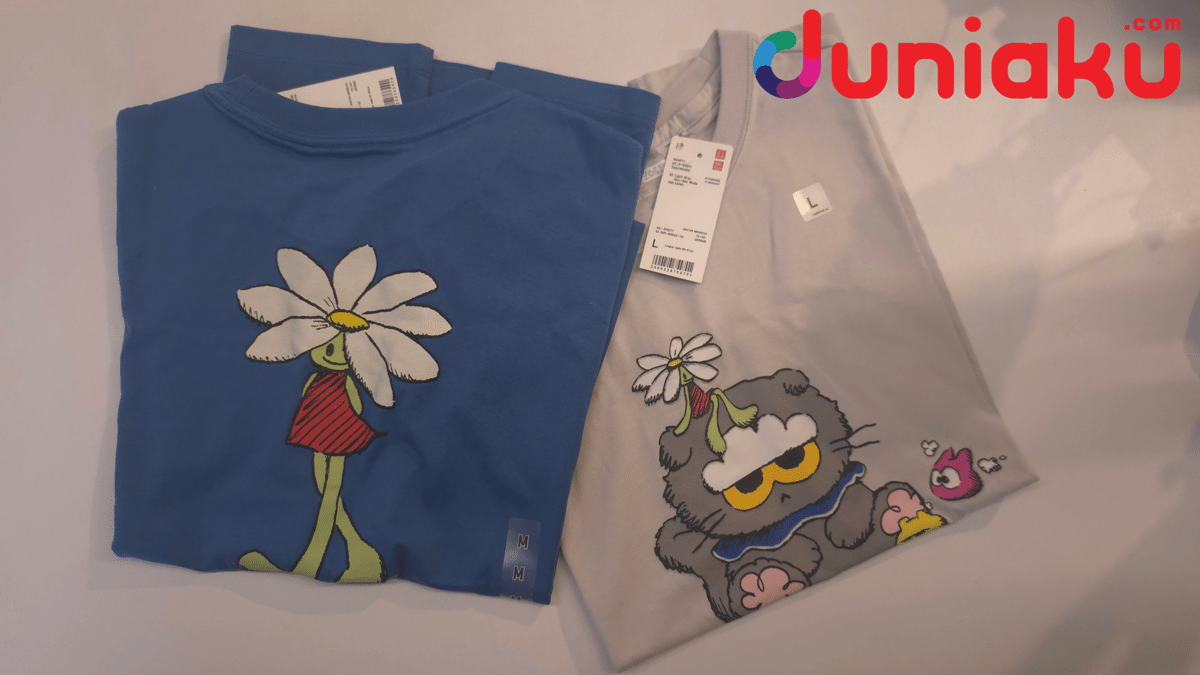 Dua kaus UNIQLO koleksi ZO&FRIENDS berwarna biru dan abu-abu dengan ilustrasi karakter lucu bergaya kartun di atas meja.