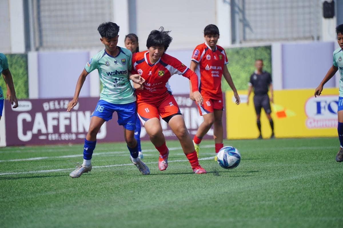 Pemain sepak bola dari dua tim berseragam merah dan hijau muda berebut bola di lapangan dalam pertandingan Hydroplus Soccer League 2025/26.