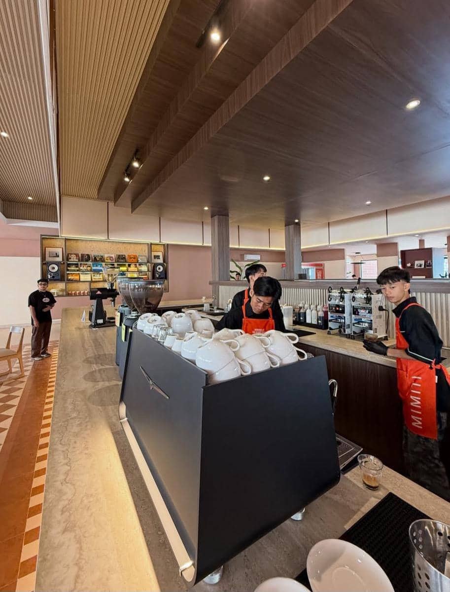 Barista mengenakan celemek oranye menyiapkan kopi di area bar Mimiti Coffee & Space yang baru dibuka di Bandar Lampung.