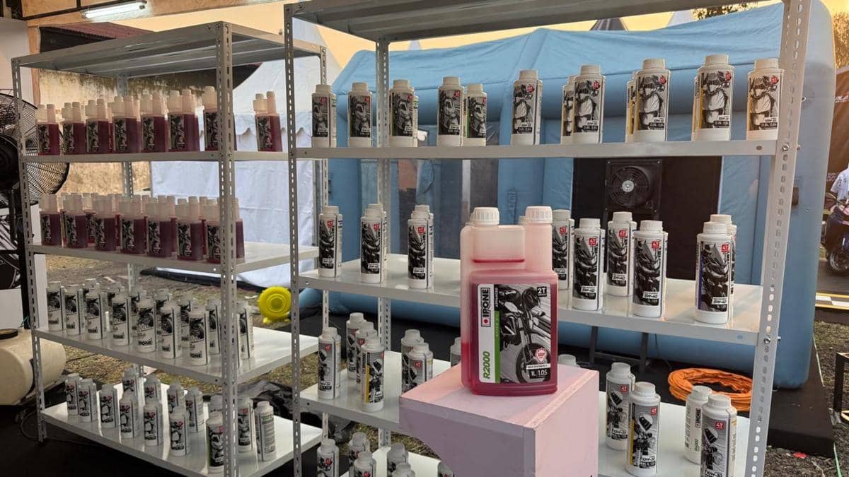 Deretan botol pelumas motor merek Ipone tersusun rapi di rak logam dengan berbagai varian produk di area pameran luar ruangan.