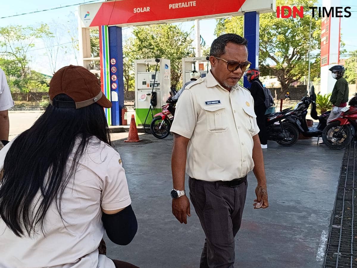 Petugas Bapenda NTT mengenakan seragam krem sedang memantau aktivitas di SPBU yang melayani bahan bakar solar dan pertalite.
