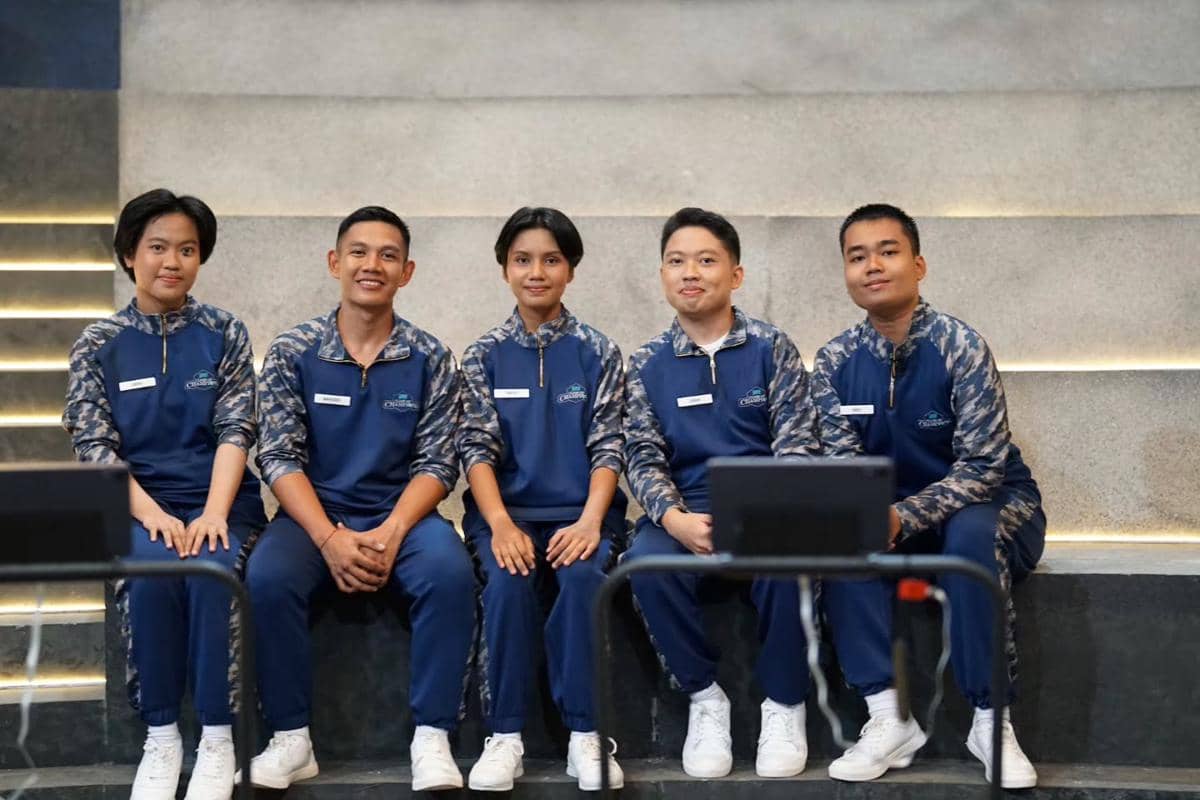 Lima peserta Clash of Champions mengenakan seragam olahraga biru duduk berjajar di tangga dengan latar dinding abu-abu modern.