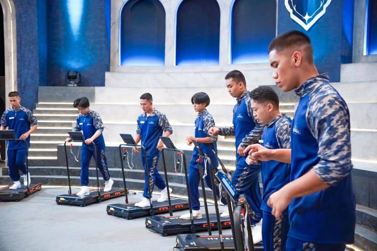 Beberapa peserta mengenakan seragam biru sedang berlari di atas treadmill sambil menjawab soal dalam acara Clash of Champions.