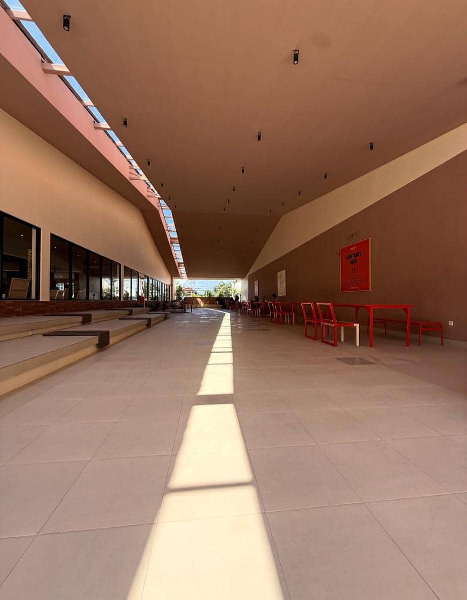 Area dalam Mimiti Coffee & Space di Bandar Lampung dengan desain modern, langit-langit tinggi, dan deretan meja kursi merah di sisi kanan.