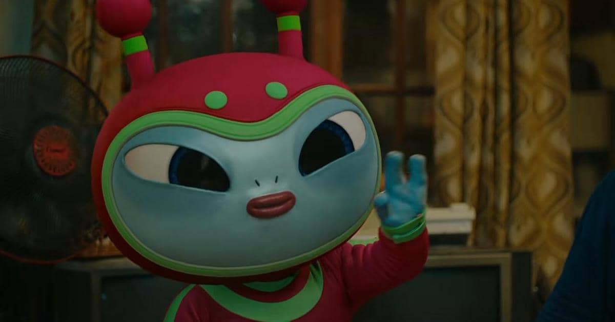 Karakter alien berwarna biru dengan kostum merah dan hijau sedang melambaikan tangan dalam cuplikan film Foufo.