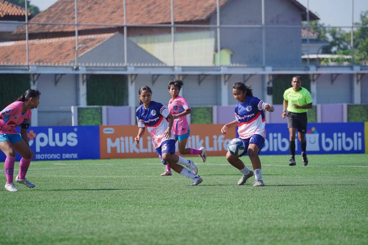 Pemain sepak bola wanita bertanding di lapangan hijau dalam ajang Hydroplus Soccer League All Stars 2025/26 dengan wasit mengawasi di belakang.