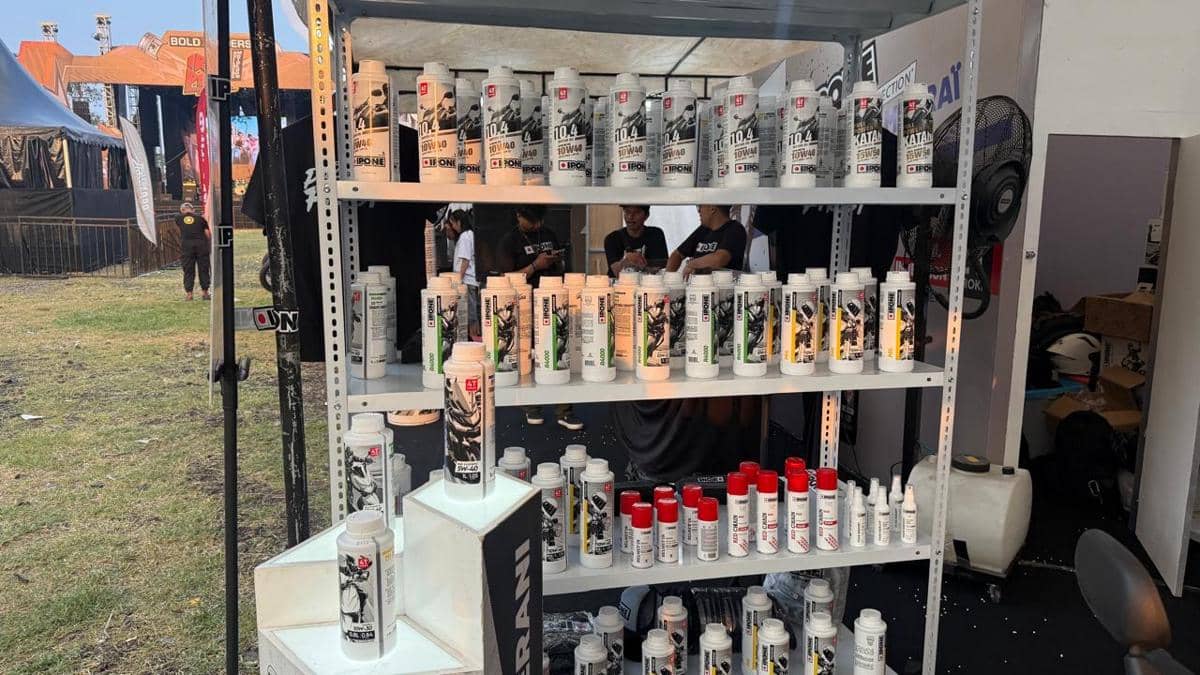 Rak berisi berbagai produk pelumas motor merek Ipone dipajang di stan pameran acara Iron Pipe 2026 dengan latar suasana luar ruangan.