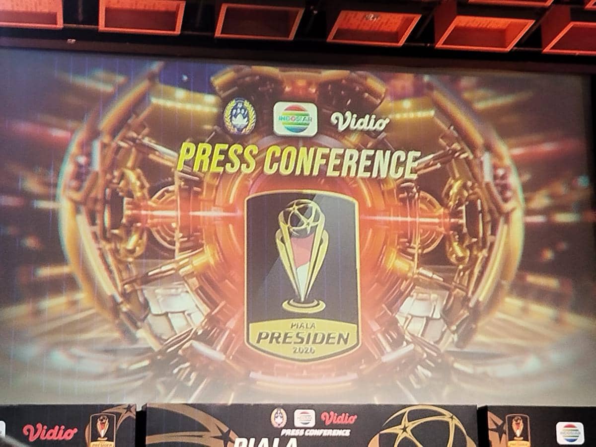 Latar panggung konferensi pers Piala Presiden 2026 dengan logo turnamen dan dekorasi berwarna emas yang futuristik.