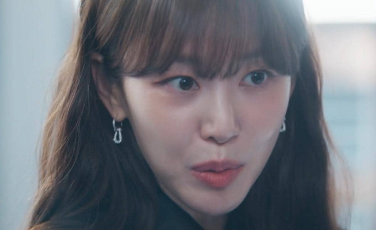 Pemeran wanita dalam drama Korea Reborn Rookie dengan ekspresi serius, mengenakan anting perak dan rambut panjang berponi.