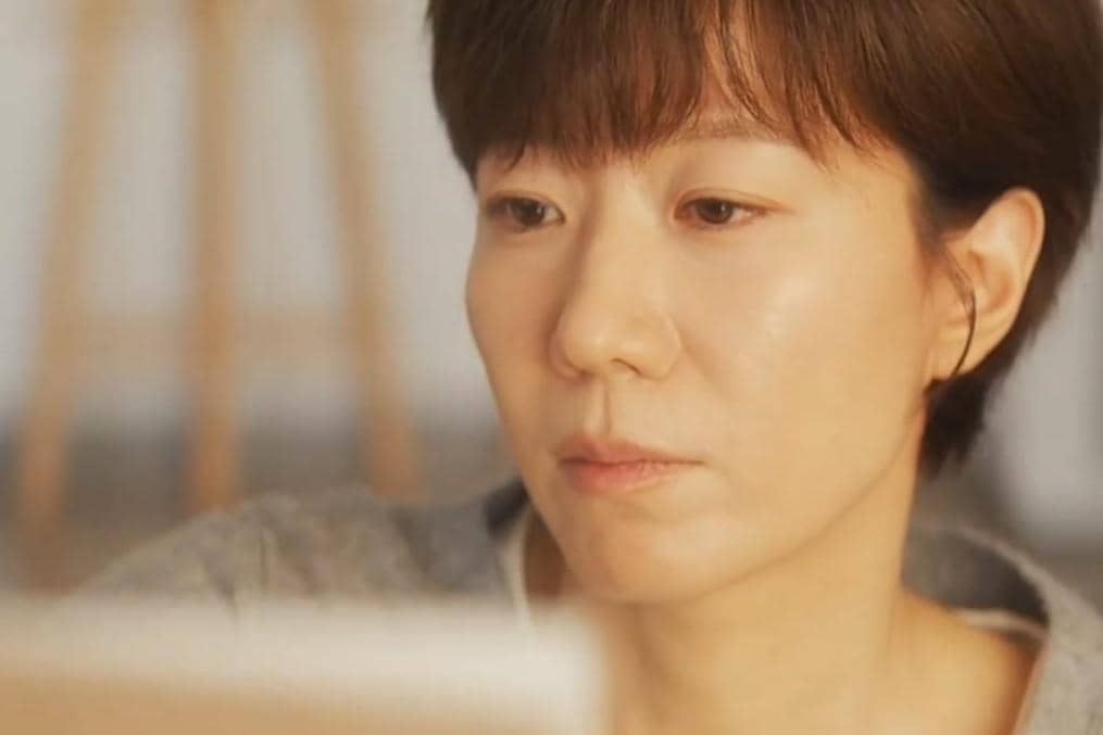 Seorang wanita berambut pendek menatap serius ke arah depan dalam cuplikan drama Korea Reborn Rookie.