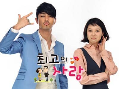 Dua pemeran utama berdiri berdampingan dalam poster drama Korea The Greatest Love, dengan ekspresi wajah lucu dan gaya unik.