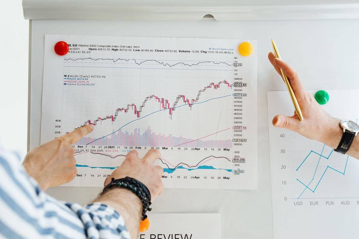 ilustrasi dua profesional menganalisis grafik pasar saham dengan fokus pada keuangan dan tren data