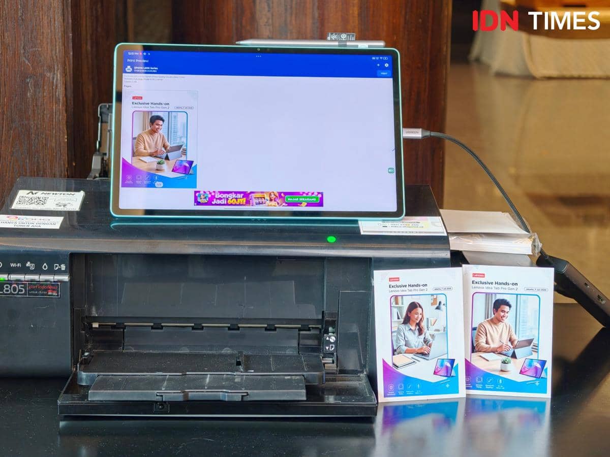 Tablet Lenovo Idea Tab Gen 2 terhubung ke printer di atas meja dengan dua brosur produk di sampingnya menampilkan pengguna tablet.