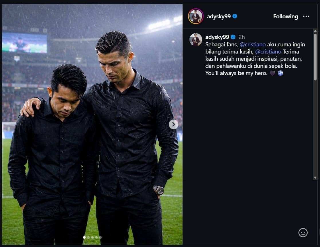 Dua pria mengenakan kemeja hitam berdiri di tengah hujan di stadion, salah satunya merangkul bahu yang lain dengan ekspresi sedih.