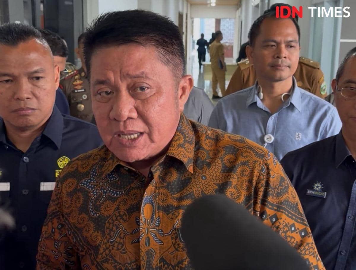 Gubernur Sumsel Herman Deru berbicara kepada media didampingi beberapa orang pria lain di sebuah koridor gedung pemerintahan.