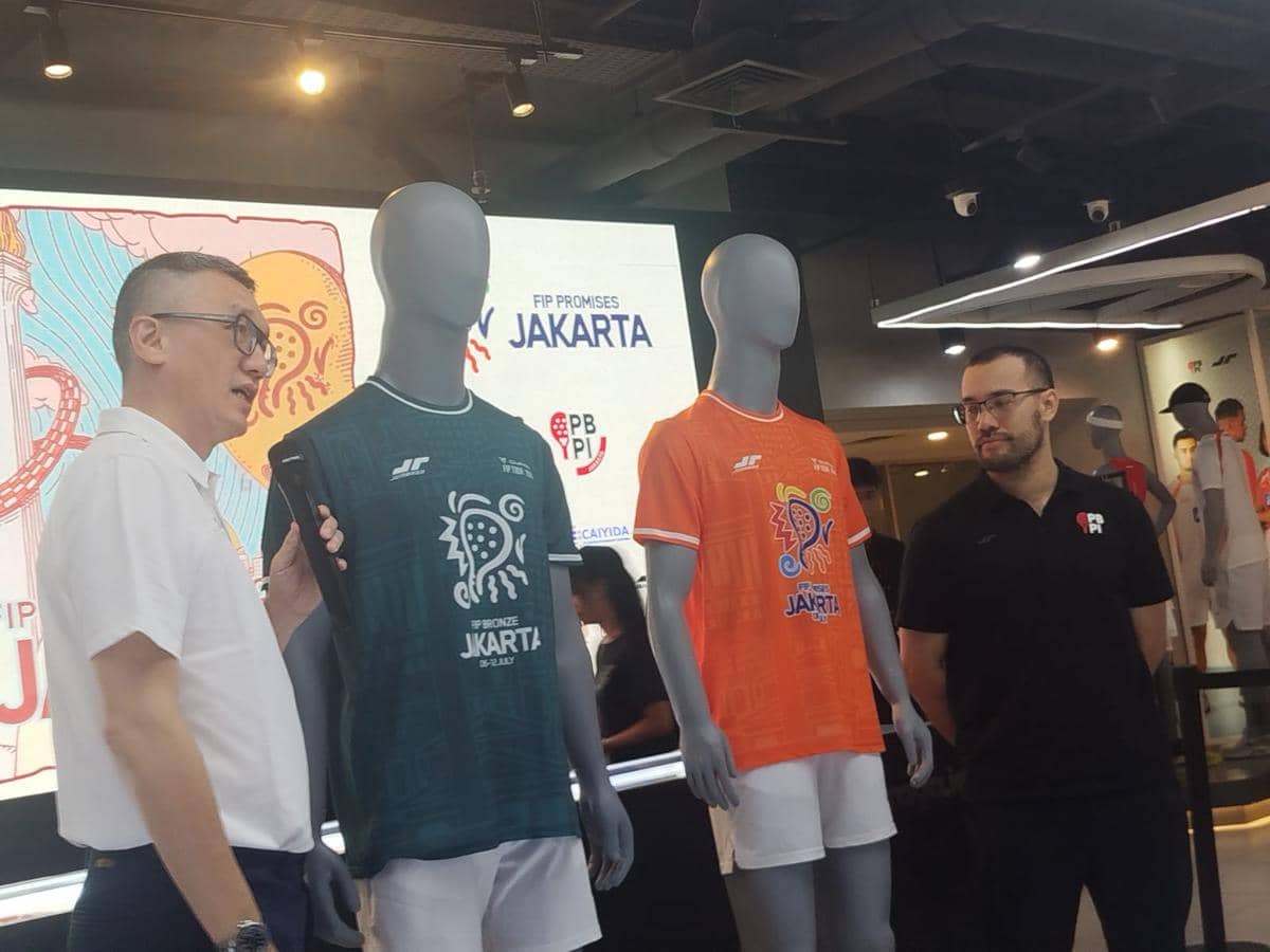 Dua orang berdiri di samping dua manekin yang mengenakan jersey FIP Promises Jakarta 2026 berwarna hijau dan oranye di sebuah acara peluncuran.