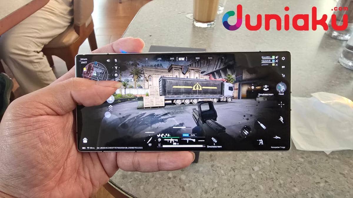Seseorang memainkan game first-person shooter di smartphone REDMAGIC 11S Pro dengan grafis detail di atas meja kafe.