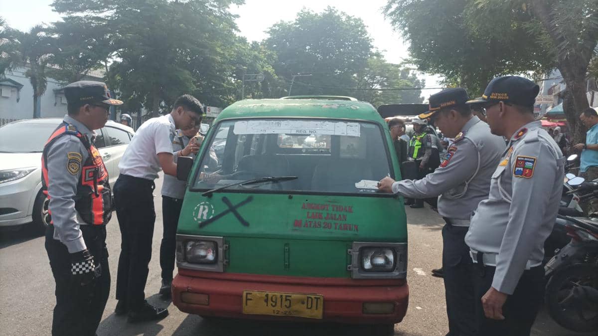 Petugas Dishub Kota Bogor memeriksa angkot tua berwarna hijau merah dalam razia kendaraan yang sudah uzur di jalan kota.