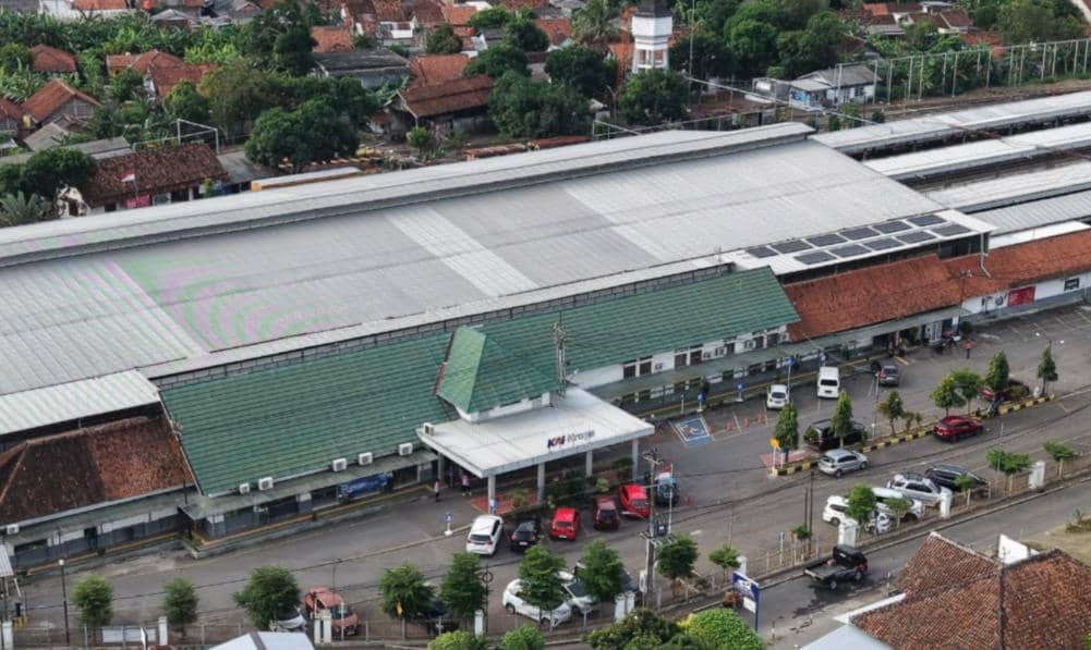Pemandangan udara Stasiun Purwokerto dengan atap terpasang panel surya sistem on grid tanpa baterai di area peron dan bangunan utama.