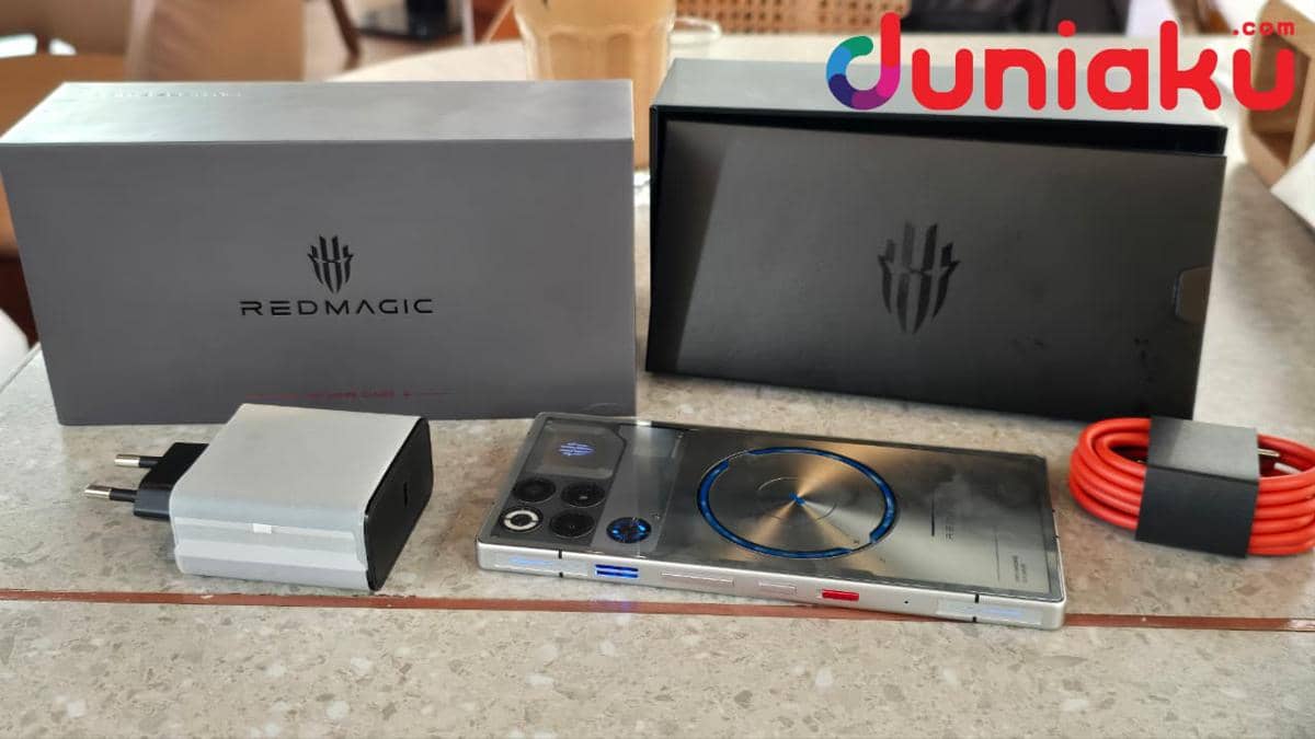 Smartphone REDMAGIC 11S Pro berwarna perak dengan desain futuristik, lengkap dengan kotak kemasan, charger, dan kabel merah di atas meja.