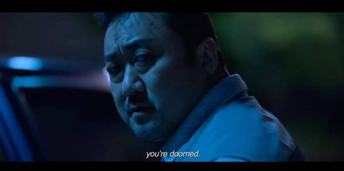 Seorang pria menatap serius ke arah kamera di malam hari dengan pencahayaan biru dalam cuplikan film Unstoppable.