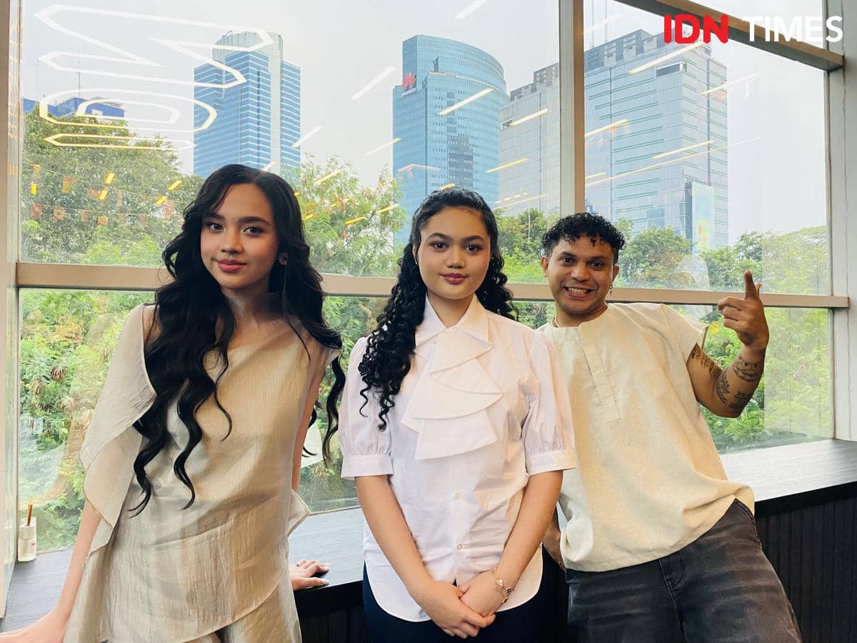 Tiga orang berpose bersama di depan jendela besar dengan latar gedung tinggi dan pepohonan di kantor IDN pada hari Selasa.