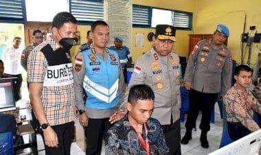 Beberapa pejabat kepolisian meninjau proses seleksi calon taruna Akademi Kepolisian di sebuah ruangan dengan peserta yang sedang menggunakan komputer.